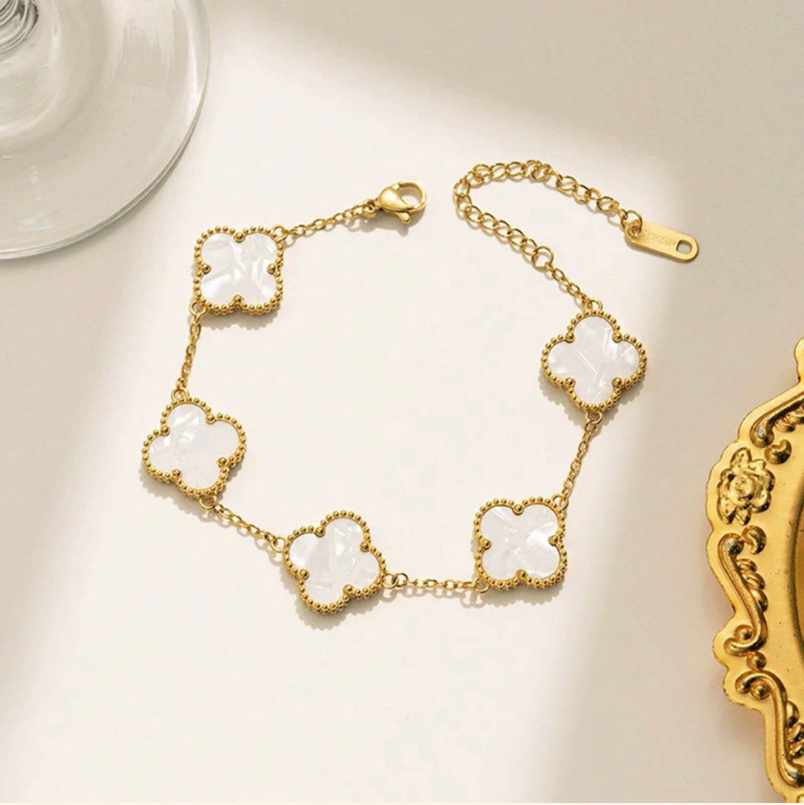 ELL DESIGNS gold bracelet with five white clover-shaped charms and adjustable chain